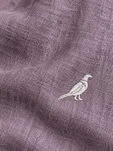 Camisa de lino color blanco, manga larga, con cuello corto clásico y bordado de un ave oscura en el pecho.