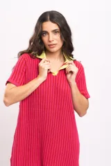 Vestido corto de punto acanalado, color fucsia, con cuello polo y solapa en contraste de color amarillo. Presenta mangas cortas y un diseño recto y relajado.