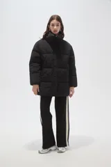 Campera puffer negra de corte holgado, con cuello alto, cierre frontal oculto y bolsillos laterales.