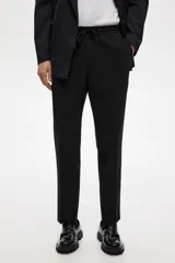 Pantalón tipo jogger de vestir negro, corte slim fit, con pliegues frontales y traseros, cintura elástica con cordón de ajuste y bolsillos laterales y traseros.