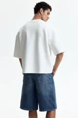Bermuda de cinco bolsillos en denim de algodón rígido, con corte holgado y pierna redondeada amplia de tiro caído.