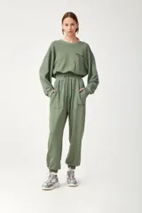 Pantalón de jogging verde militar de algodón con elástico en la cintura y tobillos, cordón de ajuste y bolsillos frontales con estampa en el bolsillo izquierdo.