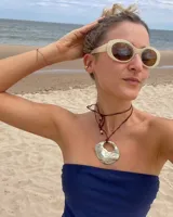 Collar artesanal con dije de bronce macizo en forma orgánica irregular, similar a una concha marina, suspendido de un cordón de seda natural negro. El diseño permite diversas formas de uso, ya sea ajustado al cuello o largo.