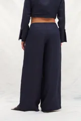 Pantalón de lino color beige y blanco, de corte amplio a la cintura y con bolsillos laterales.