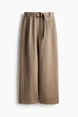 Pantalón de tiro alto con corte holgado y piernas amplias, color marrón, con pliegues delanteros y cinturón del mismo tejido con hebilla circular.