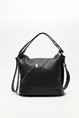 Cartera convertible en mochila, confeccionada en cuero sintético texturizado color negro. Presenta un diseño con recortes geométricos, bolsillo frontal con cierre diagonal y herrajes metálicos plateados. Incluye asa superior para llevar al hombro y correas regulables.