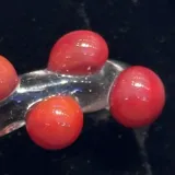 Anillo artesanal de vidrio transparente con diseño irregular y esferas decorativas de color rojo.