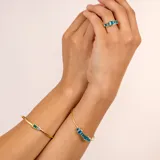 Brazalete abierto dorado en plata 925 bañada en oro de 18k con piedras topacio azul y jade verde.