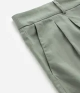 Bermuda de corte sastrero color verde oliva, confeccionada en mezcla de viscosa y lino. Presenta pliegues frontales, bolsillos laterales, trabillas para cinturón y cierre frontal con botón y cremallera.