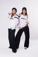 Pantalón de jean negro de corte wide leg y tiro bajo, confeccionado en tela rígida sin elasticidad.