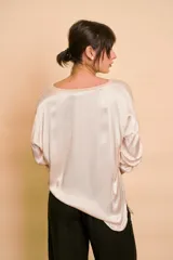 Blusa holgada de satén color beige, con escote en V y mangas largas con trabilla para sujetar remangadas.