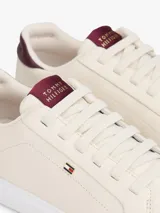 Zapatillas Tommy Hilfiger de diseño bajo color beige, con detalles en tono bordó en el talón y la lengüeta, suela blanca y logo distintivo de la marca en el lateral.