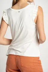 Musculosa negra de viscosa con cuello redondo y detalle de volados en los hombros. Presenta un corte holgado y fluido con un pequeño aplique metálico en el ruedo.