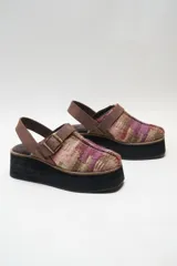 Zueco con plataforma alta, capellada de tela estampada en tonos azules y verdes, con detalles de cuero marrón y hebilla dorada.
