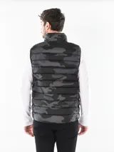 Chaleco acolchado de la marca Calvin Klein con estampado de camuflaje en tonos gris y negro. Presenta un diseño ligero con cuello alto, cierre frontal de cremallera y el logotipo de la marca en el pecho.