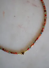 Collar de cuentas cuadradas de cristal multicolor con esferas doradas y un dije de estrella dorada.