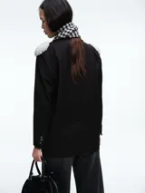 Blazer negro de corte estructurado con hombreras decoradas con apliques de perlas. Presenta cierre frontal con un botón, solapas clásicas y bolsillos laterales con solapa.