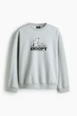 Buzo gris melange de corte holgado, con hombros caídos, cuello redondo, puños y dobladillo acanalados. Cuenta con un estampado frontal de Snoopy en el centro del pecho.