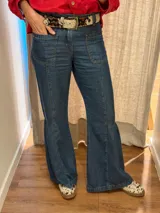 Jean de denim azul con bolsillos delanteros aplicados, costuras verticales y diseño de tablas en los laterales de las piernas amplias.