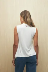 Top sin mangas color negro, con cuello alto y terminación en pico en la parte inferior, con un detalle de frunce o abertura en el lateral.