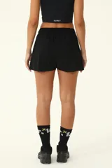 Short deportivo negro con diseño de falda con tablas encontradas en el frente y bolsillos laterales.