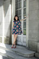 Vestido corto sin mangas de corte recto y holgado, confeccionado en lino con estampado floral multicolor sobre fondo azul oscuro. Presenta cuello redondo y cierre posterior con botones forrados.