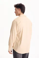 Camisa de lino de manga larga, color beige, con cuello clásico y cierre frontal de botones.