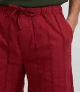 Bermuda recta de playa en color blanco roto, confeccionada en algodón texturizado con efecto de rayas verticales. Posee cintura elástica con cordón ajustable.