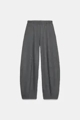 Pantalón de tiro alto con pierna ancha y cintura elástica ajustable. Presenta un diseño de corte holgado con costuras verticales frontales que definen su silueta.
