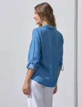 Camisa celeste de lyocell, con cuello a la base, escote en V y abertura central con botones. Tiene bolsillos aplicados en la parte delantera y mangas 3/4 regulables con presilla y botón.