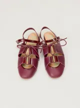 Sandalias planas tipo slingback de cuero marrón, con diseño delantero calado, cierre de cordones y tira trasera ajustable con hebilla.