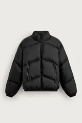 Cazadora puffer acolchada de corte relaxed fit, color negro, con cuello subido y cierre frontal con cremallera. Cuenta con bolsillos laterales con cierre de cremallera, mangas largas y terminaciones elásticas.