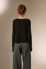 Top de manga larga color negro, con escote cuadrado y detalle de nudo frontal que genera una abertura central. Confeccionado en tejido de poliéster con ajuste al cuerpo.