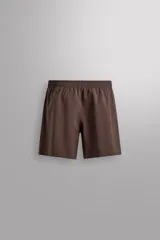 Pantalones deportivos cortos de Zara Athleticz, confeccionados en tejido técnico ligero y elástico. Presentan cintura elástica ajustable con cordón interior, bolsillos frontales, bajo con perforaciones decorativas y aberturas laterales, con detalle de logo estampado en la pierna.