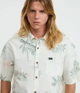 Camisa de hombre de corte relajado, color blanco con estampado de palmeras y paisajes playeros. Tiene cuello inglés, manga corta, abotonadura frontal y bolsillo en el pecho.