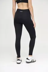 Calza deportiva negra con cintura alta y compresión media. Presenta una franja vertical blanca a lo largo de la pierna.