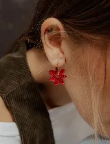 Aros de argolla metálica con dije colgante en forma de flor de acrílico color rosado.