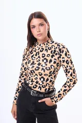 Remera de manga larga con cuello alto, confeccionada en algodón con estampado animal print de leopardo en tonos beige, negro y blanco. Presenta un corte ajustado al cuerpo.