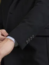 Blazer negro de corte clásico con dos botones frontales, solapa de muesca y bolsillos laterales.