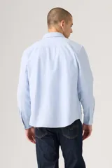 Camisa celeste de manga larga con cuello abotonado y cierre frontal de botones. Confeccionada en algodón con sutil bordado en el pecho.