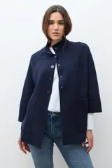 Chaqueta corta de tejido de punto color azul marino, con cuello mao abotonado y mangas tres cuartos. Presenta bolsillos frontales amplios.