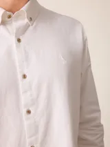 Camisa de manga larga confeccionada en algodón oxford, con cuello abotonado y cierre frontal de botones. Presenta un diseño clásico y minimalista con un pequeño logo bordado en el pecho.