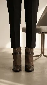 Bota corta de diseño sofisticado que combina texturas. Presenta puntera en cuero grabado tipo croco y caña en gamuza suave. Incluye una correa decorativa con hebilla metálica en el tobillo y taco bajo.