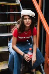 Remera corta roja con cuello redondo, manga corta y estampado frontal con la frase "latina baby" en azul.