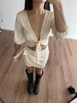 Minifalda tipo wrap de color crudo, con diseño cruzado y lazo lateral ajustable. Confeccionada en tela slab.