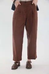 Pantalón de lino marrón de tiro medio, con calce holgado y diseño de piernas amplias. Cuenta con bolsillos traseros, trabillas para cinto y un pin bordado en contraste.