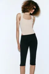 Body de tejido elástico color beige, sin mangas y con diseño de escote cuadrado. Cuenta con cierre en la parte inferior con botones a presión.