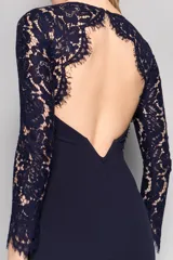 Vestido largo de fiesta color azul marino, con mangas largas de encaje y escote redondo. Presenta un diseño entallado que se ensancha suavemente hacia el ruedo.