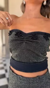 Top strapless tejido con hilo lurex negro y dorado, con escote corazón y detalles de apliques de crochet negros en el borde superior.