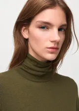 Vestido largo verde militar de punto, con cuello alto, manga larga y detalle de hebilla metálica en la cadera.